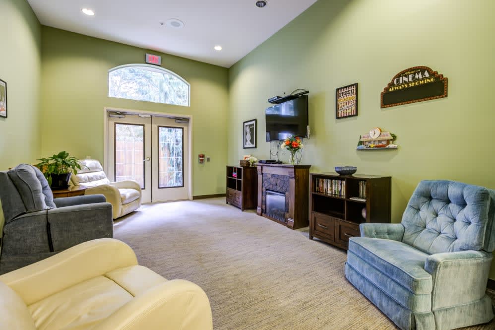 Cozy living room with green walls and comfortable seating around a television.