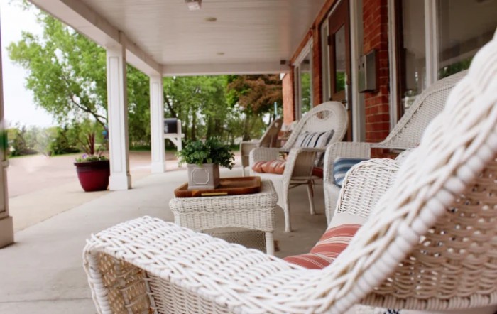 A cozy porch with wicker furniture and potted plants, perfect for relaxation.