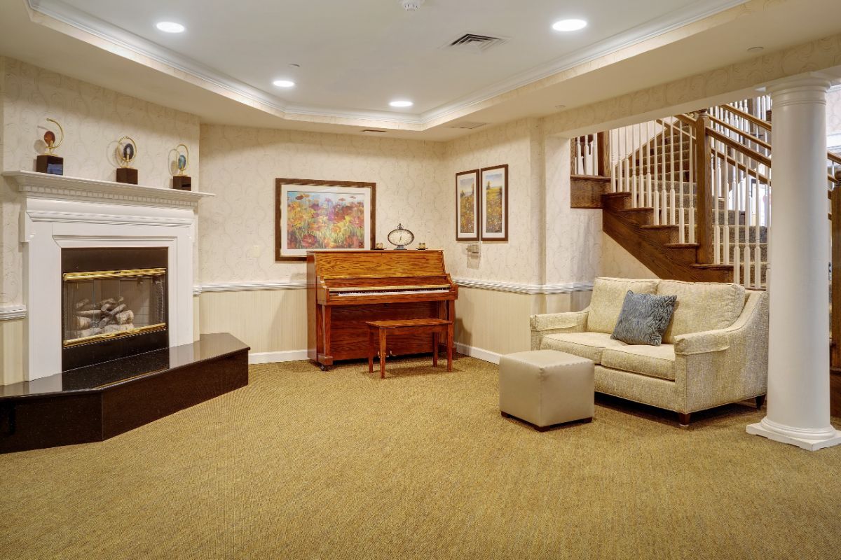 A cozy living room featuring a piano, fireplace, and staircase.