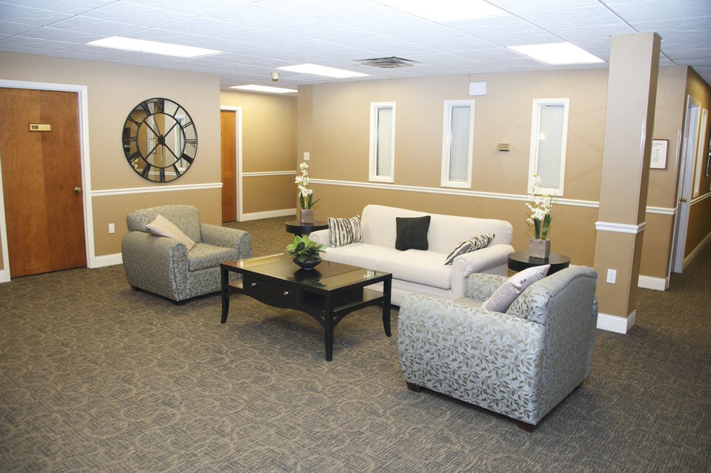 A cozy living room featuring a sofa, armchairs, and a coffee table, with decorative elements including a large wall clock.