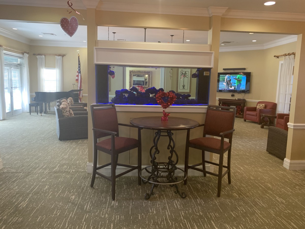 A cozy lobby area featuring a table with chairs, a television, and decorative elements.