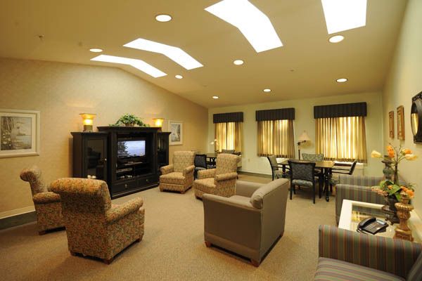 A cozy living room with comfortable seating and a television, illuminated by skylights.