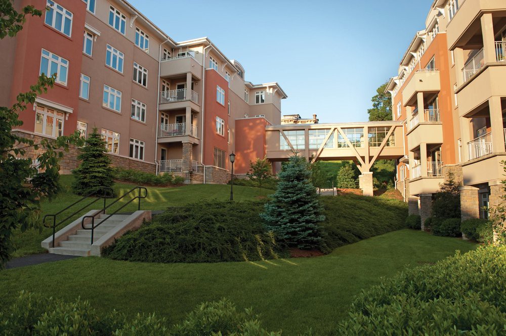 A residential complex with a connecting bridge and landscaped greenery.