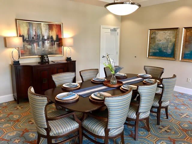 A well-furnished dining room with a set table, elegant chairs, and artwork on the walls.