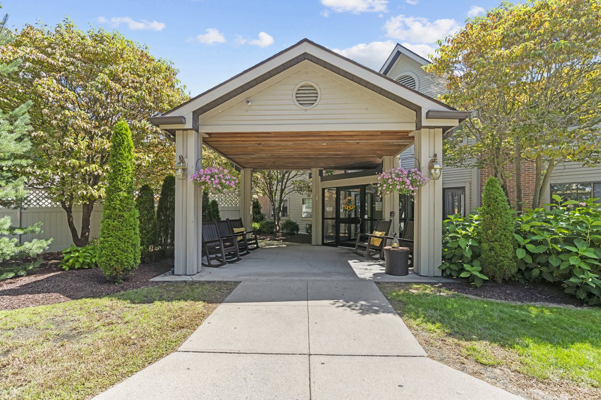 A building entrance with a canopy surrounded by trees and landscaping.