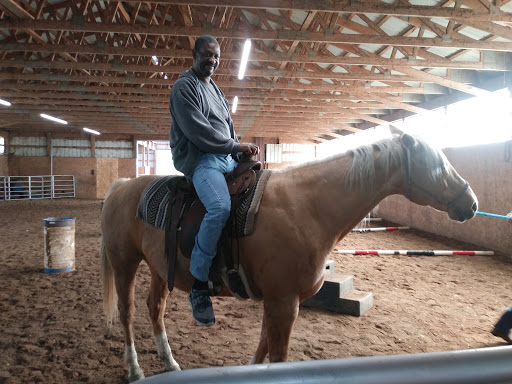A man riding a horse inside an indoor arena.