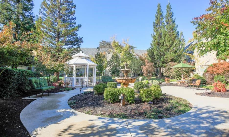A beautiful garden featuring a gazebo, fountain, and well-manicured landscaping.