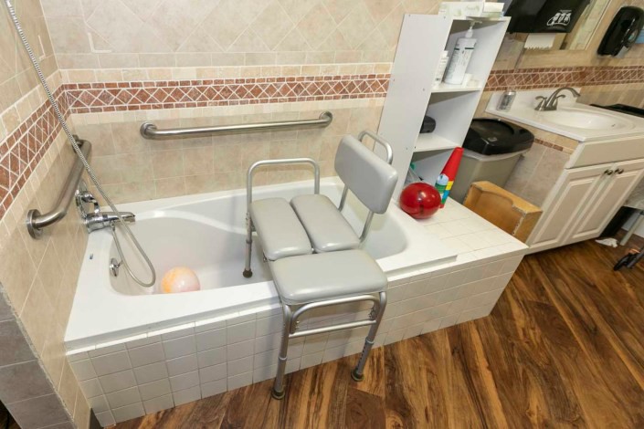 An accessible bathroom setup with a shower chair placed over the bathtub for safety and convenience.