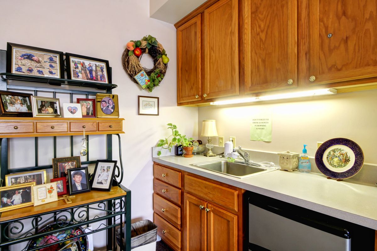 A cozy kitchen corner featuring wooden cabinets, a small sink area, and decorative elements such as a wreath and framed pictures.