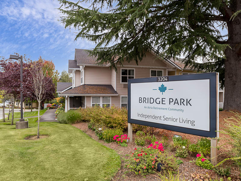 A senior living facility with a well-maintained garden and clear signage under a cloudy sky.