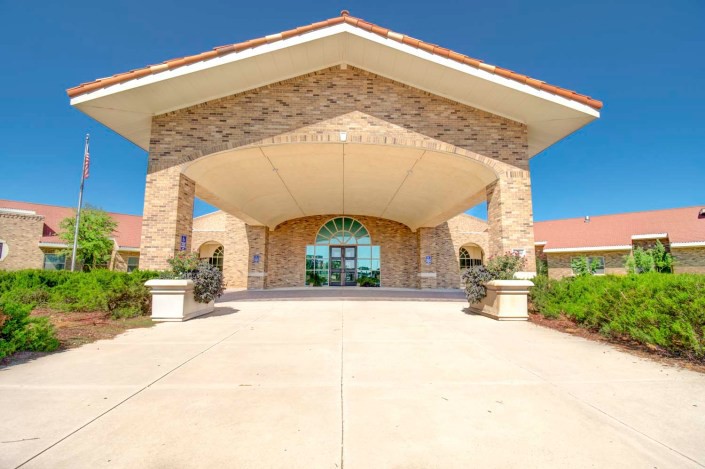 A symmetric building entrance with a brick facade and a large overhanging awning.