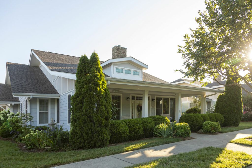 A charming residential house with a porch, surrounded by a well-maintained garden and trees.