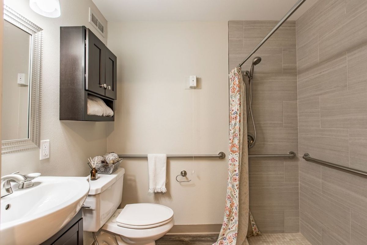 A clean and modern bathroom with a shower and cabinet.