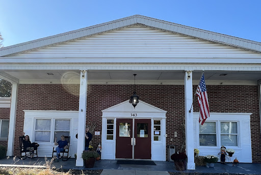 A welcoming entrance to a building, featuring classic architecture and an American flag.