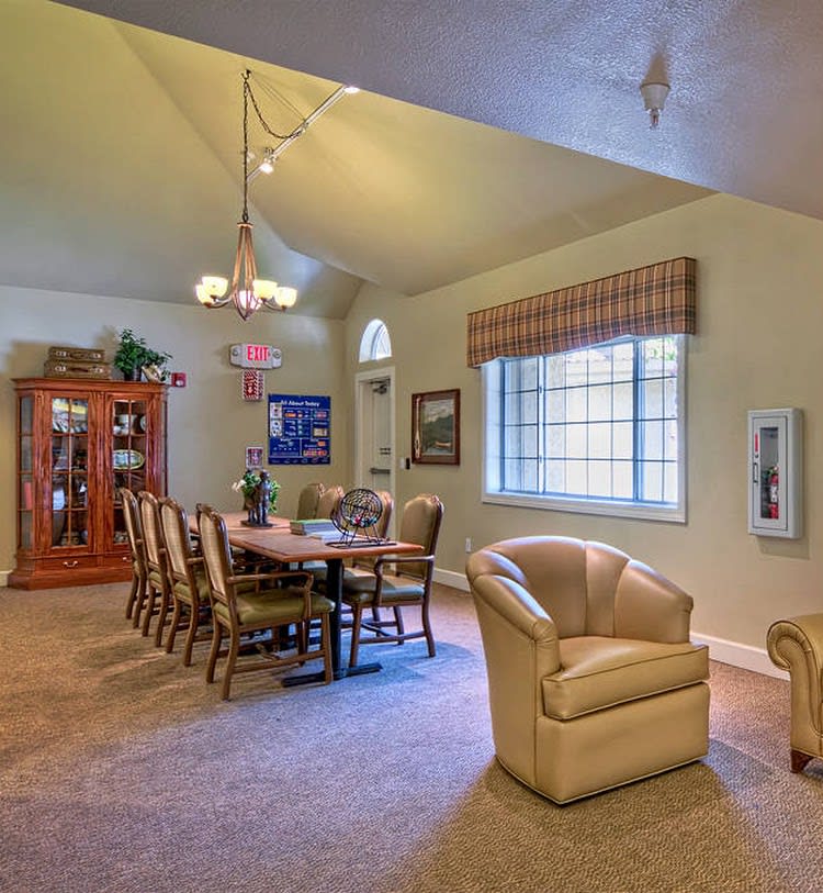 A cozy dining room with a large table and chairs, featuring a window and a cabinet against the wall.