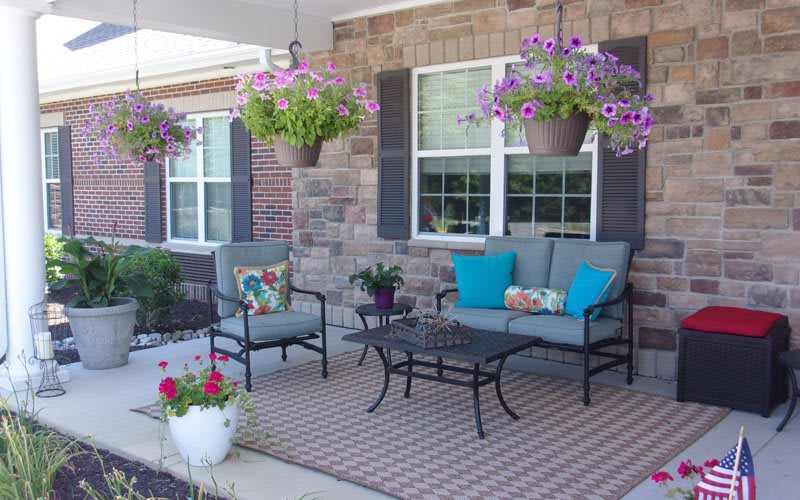 A cozy porch with outdoor seating and vibrant hanging plants.