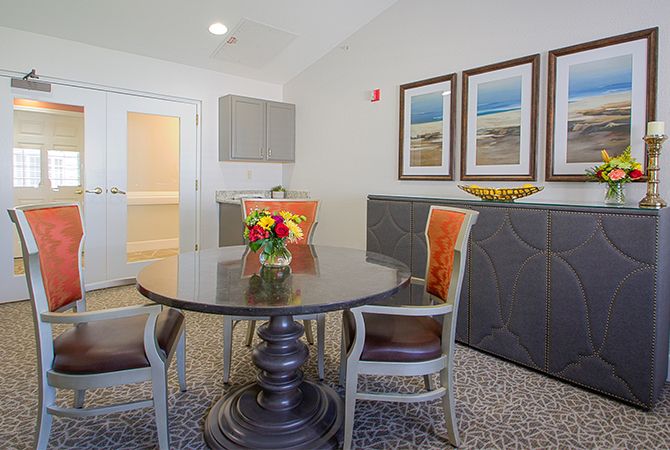 A modern dining area featuring a dark wooden table with chairs, decorated with vibrant flowers and framed artwork on the walls.