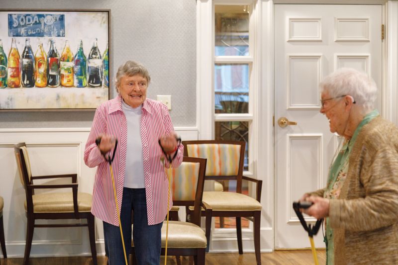 Elderly individuals participating in a group exercise session using resistance bands indoors.