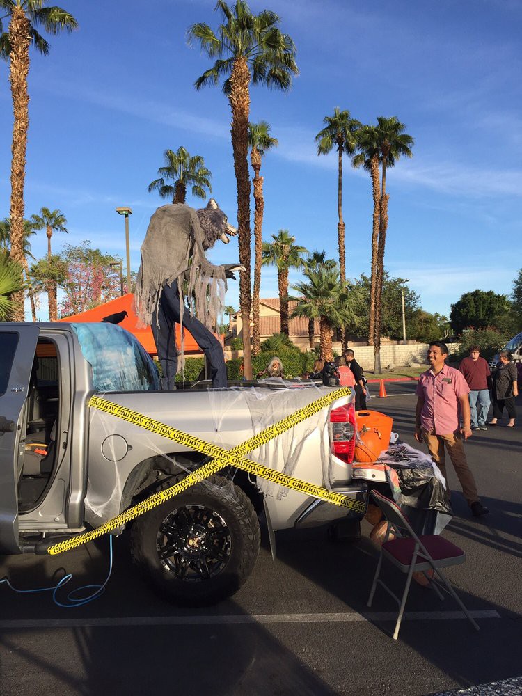 A truck decorated with a werewolf figure for a Halloween event, with people gathered around.