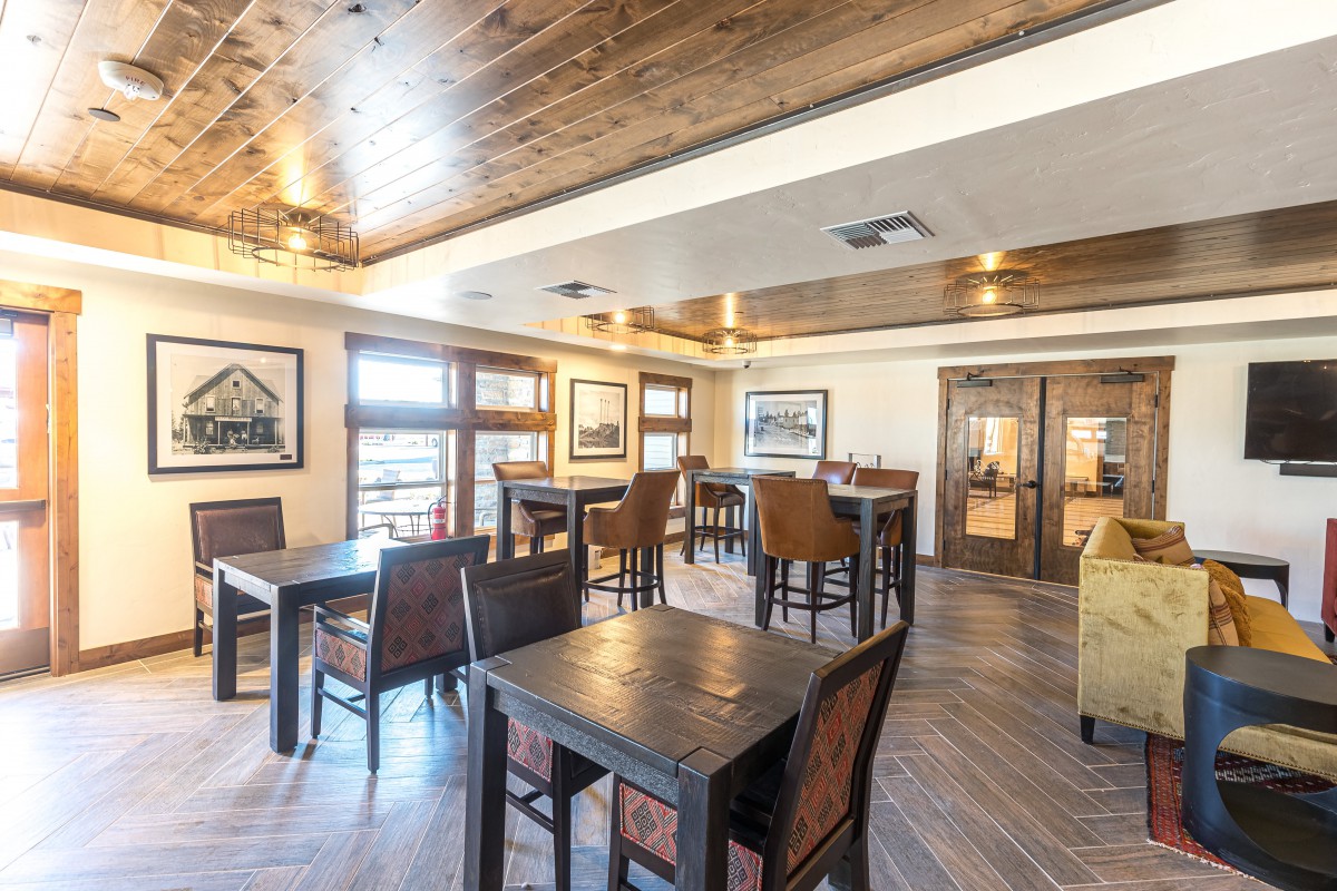 A cozy dining area featuring wooden tables and chairs with warm lighting.