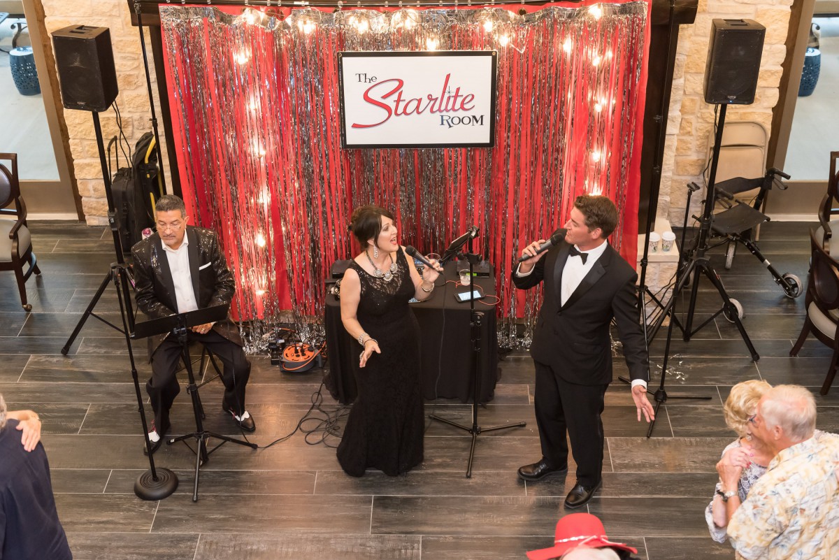 A formal musical performance with singers and a musician on stage.