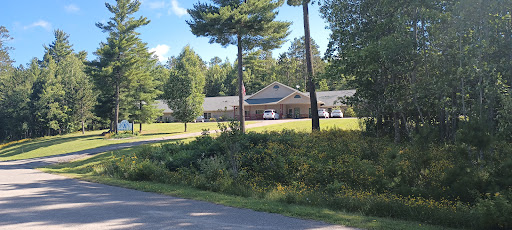 A scenic view featuring a building surrounded by trees and lush greenery, with a road in the foreground.