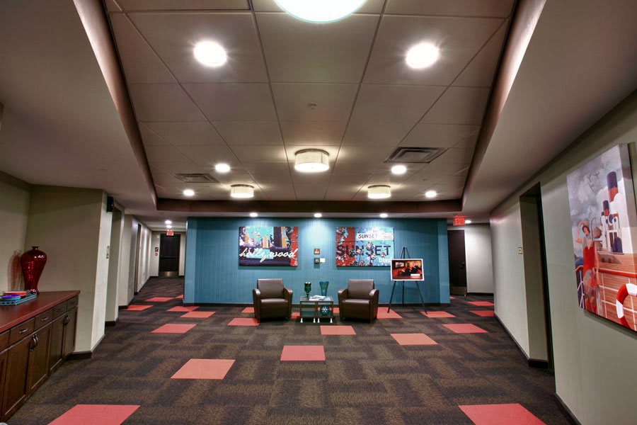 A modern lobby with colorful carpet tiles, artwork on the walls, and seating arrangements.