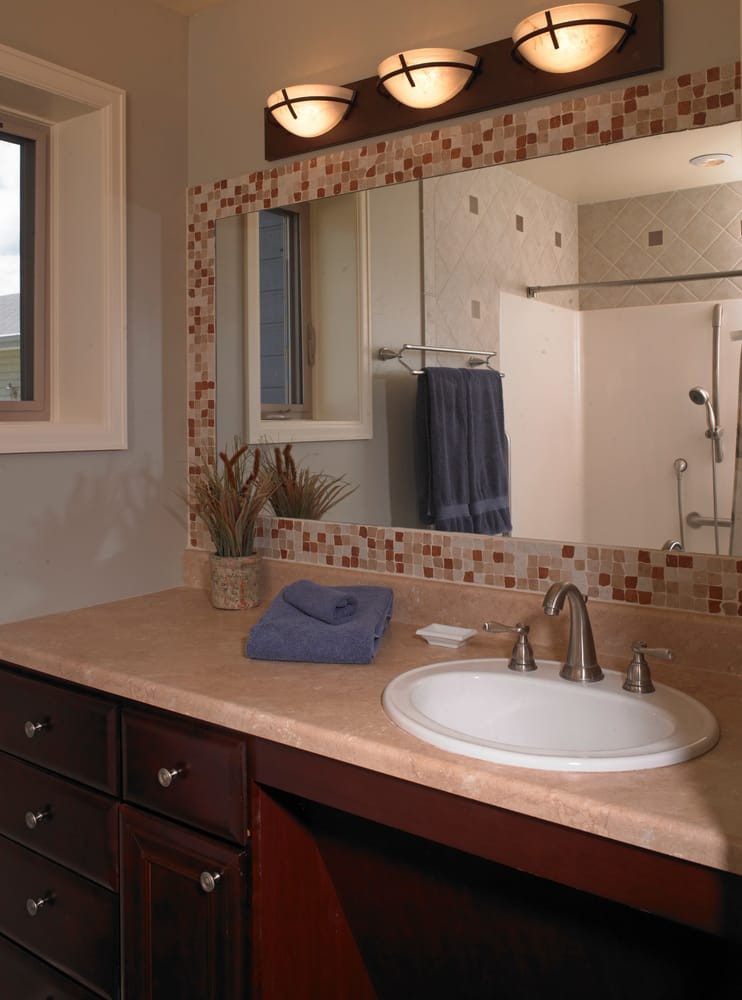 A clean and organized bathroom with a mirror above the sink, neatly folded towels, and decorative elements on the countertop.