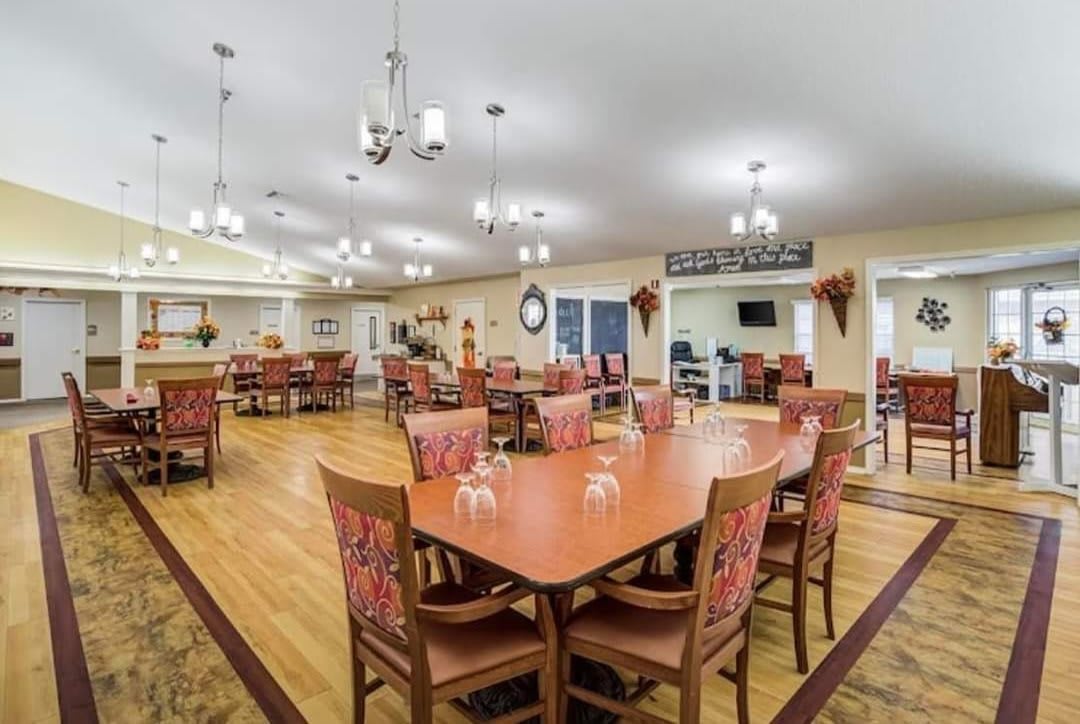A spacious dining area with neatly arranged tables and chairs, illuminated by elegant chandeliers.