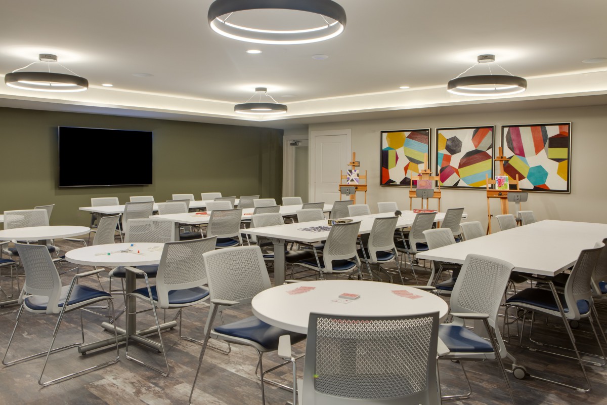 A modern conference room with circular tables, mesh chairs, and colorful artwork on the walls.