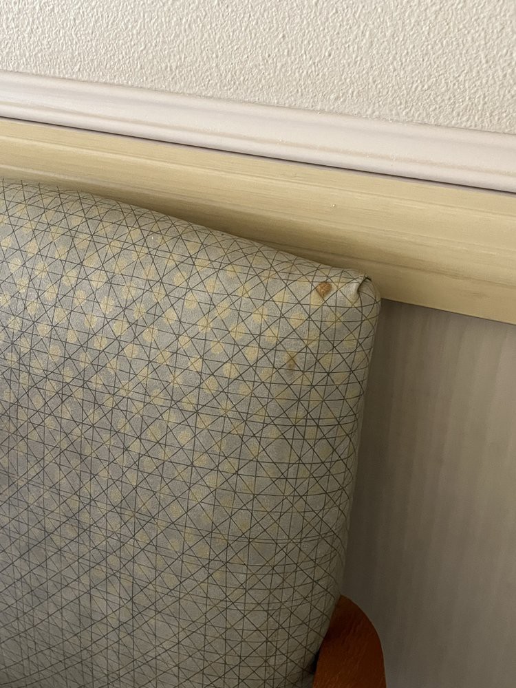 Close-up of a patterned upholstered headboard against a wall.