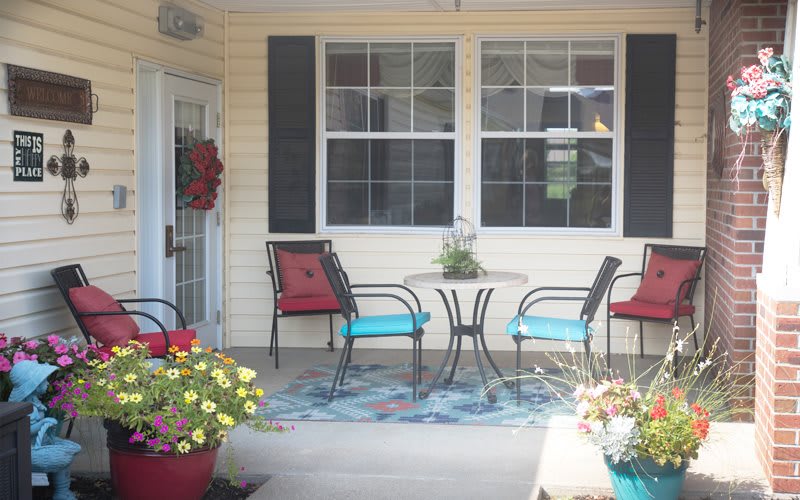 A cozy patio with chairs, a table, and colorful flowers.