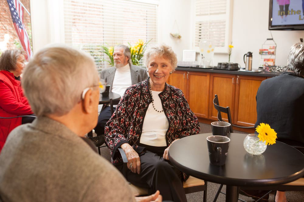 A group of senior individuals enjoying a conversation over coffee in a cozy indoor setting.