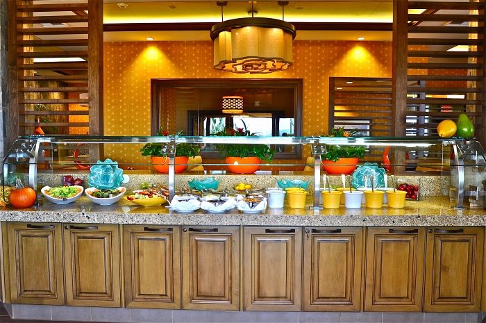 A vibrant buffet display in a restaurant, showcasing a variety of dishes under warm decorative lighting.