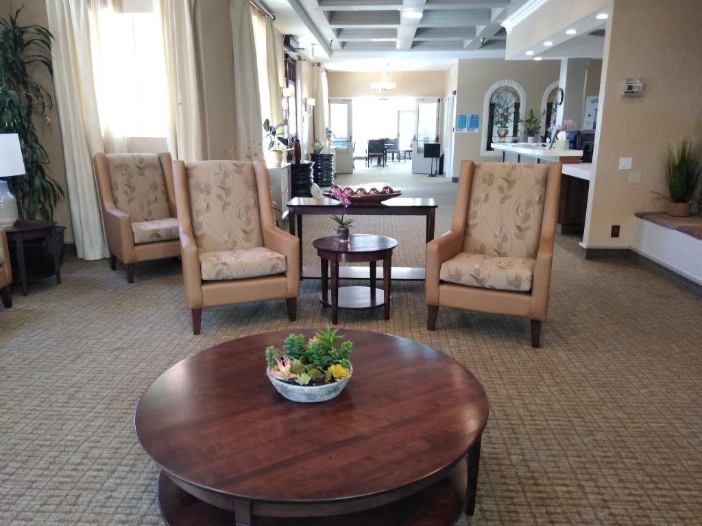 A cozy lobby area featuring comfortable chairs and a center table with decorative plants.