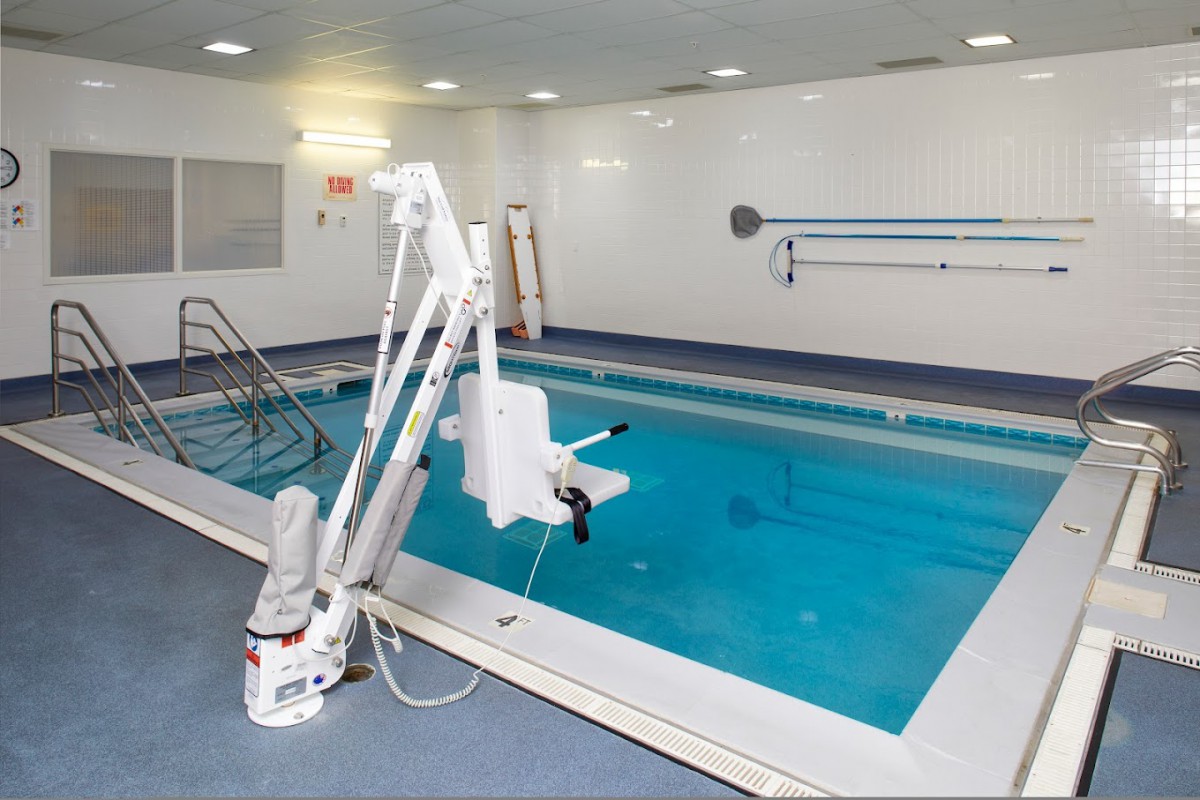 An indoor swimming pool equipped with an accessibility lift for hydrotherapy and rehabilitation exercises.
