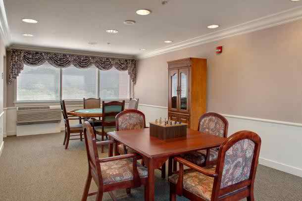 A dining room with tables, chairs, and a cabinet by the window.