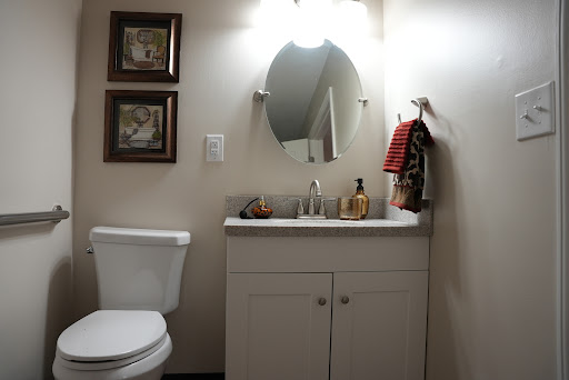 A compact bathroom featuring a vanity with a sink, a toilet, and decorative elements on the walls.