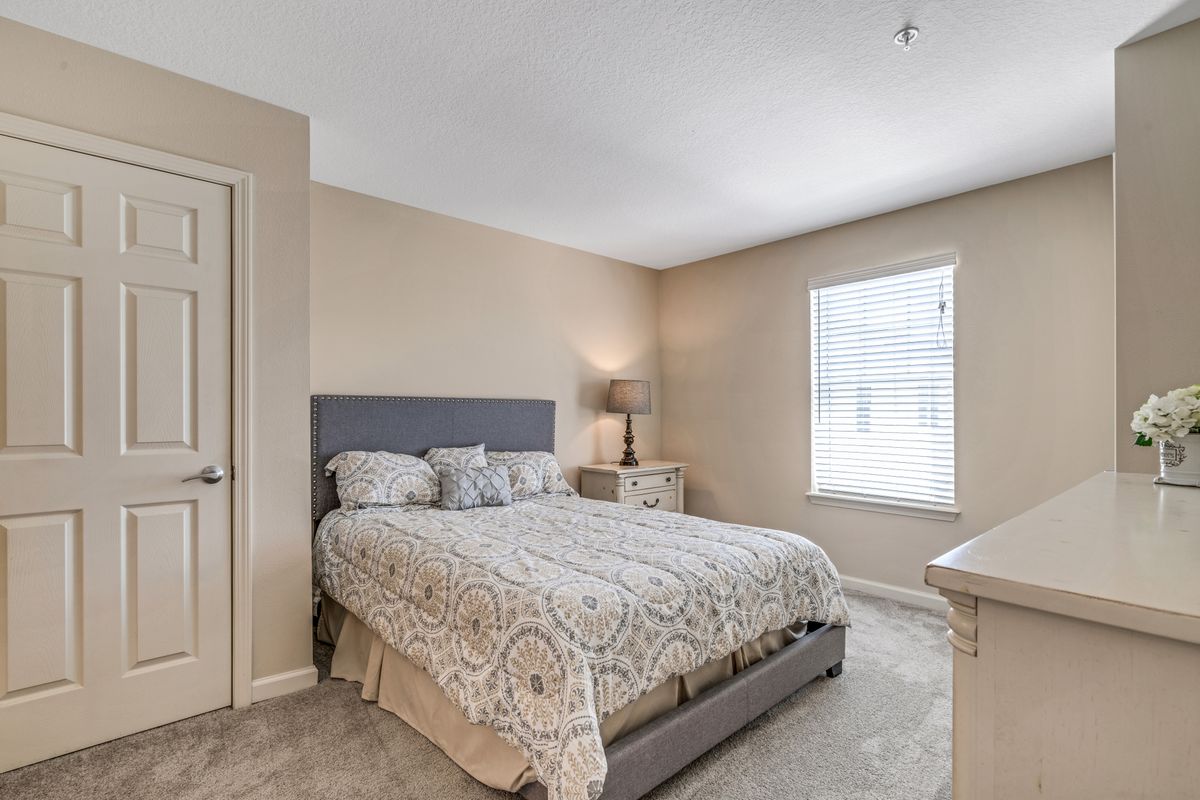 A cozy bedroom with a large bed, nightstands, and a lamp next to a window.
