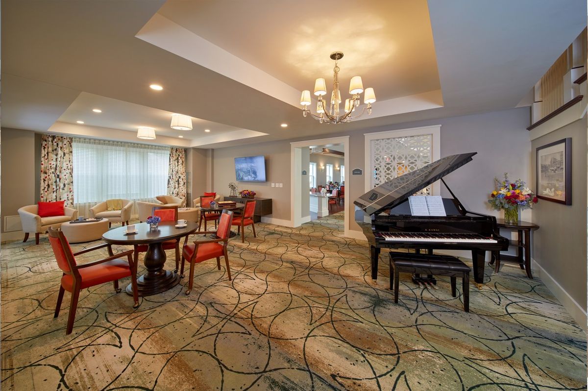 A luxurious living room with a grand piano, elegant chandelier, and comfortable seating area.