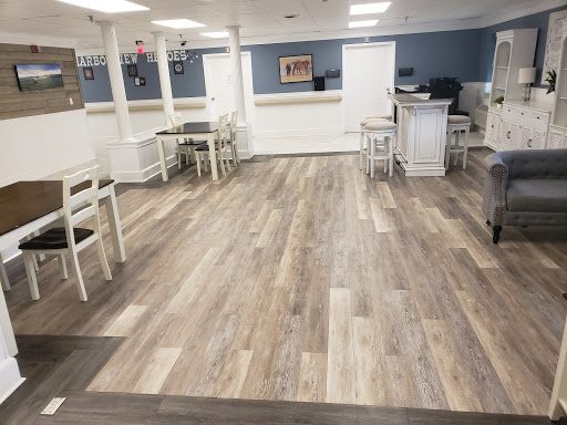 A spacious and modern dining area featuring wood-like flooring and simple white furniture.