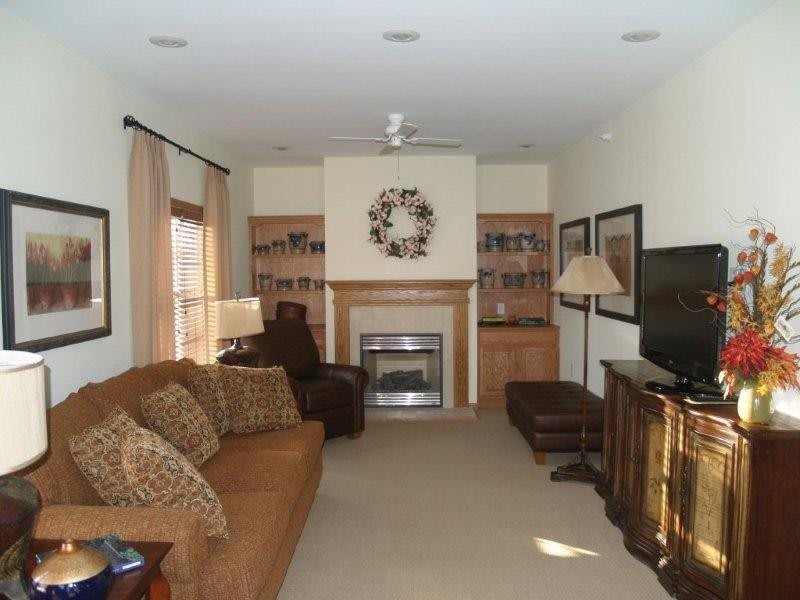 A cozy living room featuring a brown sofa, fireplace, and television.