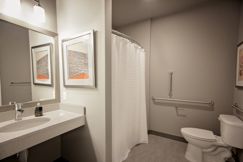 A modern bathroom with a shower curtain, toilet, and sink.