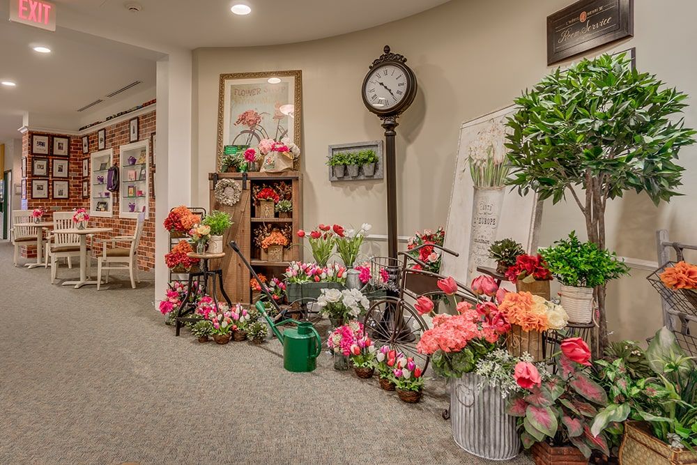 An indoor space beautifully decorated with a variety of colorful flowers and a vintage clock.