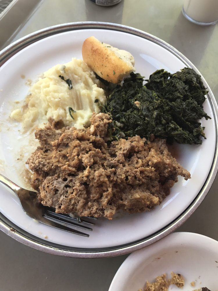 A plate featuring mashed potatoes, greens, and meat with gravy.