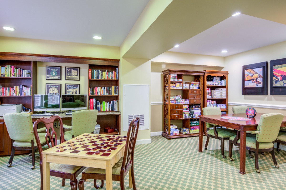 A cozy library space with bookshelves, a table for board games, and a computer for studying.