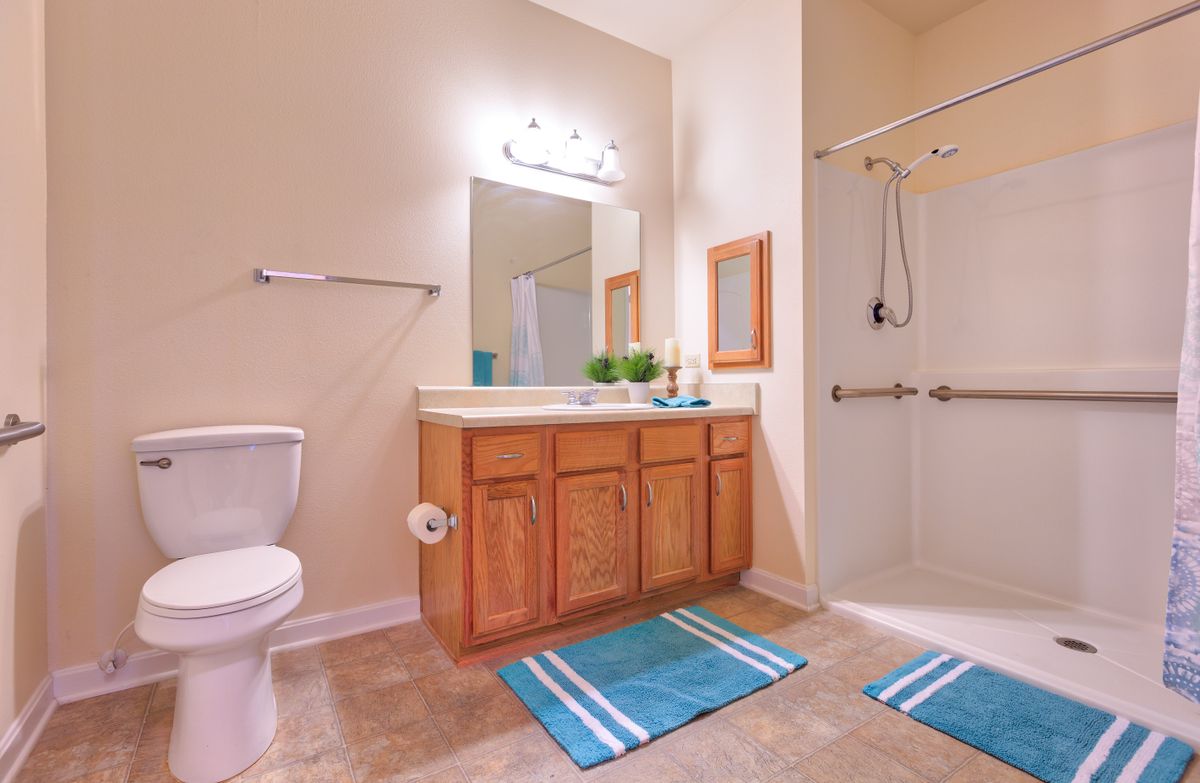 A modern bathroom with a wooden vanity, large mirror, and walk-in shower.