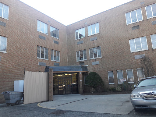 An exterior view of a brick apartment building featuring multiple windows and an entrance.