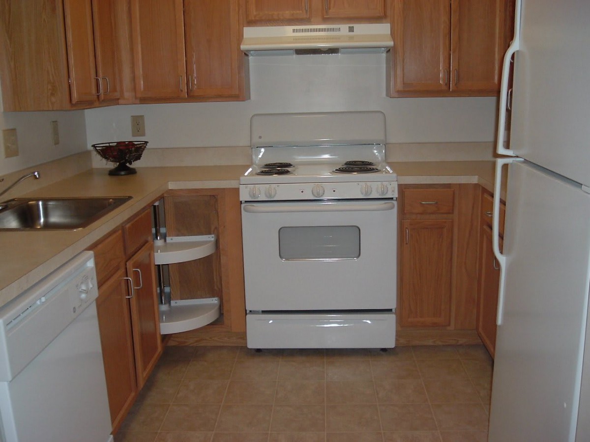 A clean kitchen with wooden cabinets and a white stove.