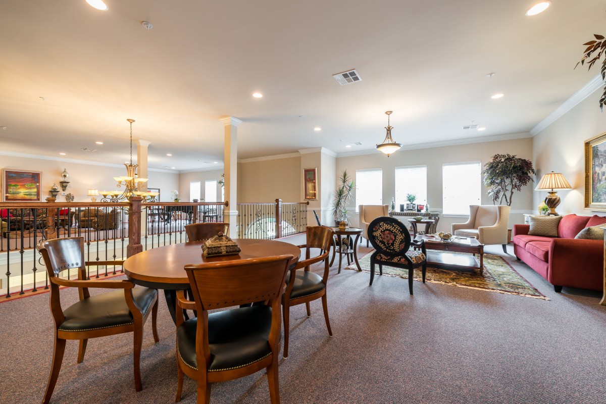 A spacious dining and living area with multiple tables, chairs, and ample lighting.